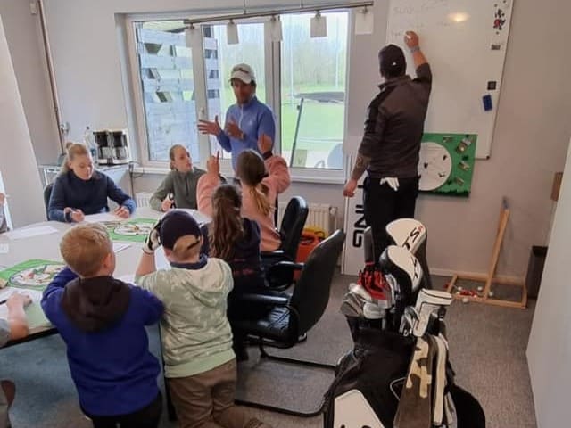 ein golflehrer lehrt junge golfschüler in einem raum